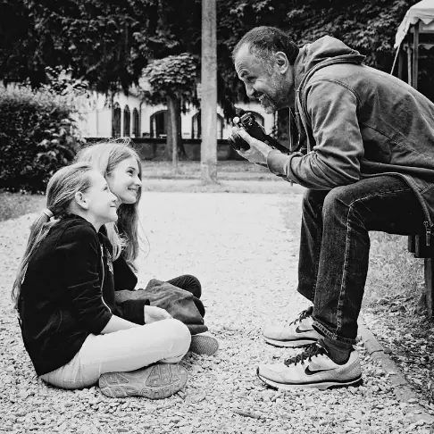 Schwarz-weiß Aufnahme zeigt den Photografen Pietro Sutera im Gespräche mit zwei Kindern